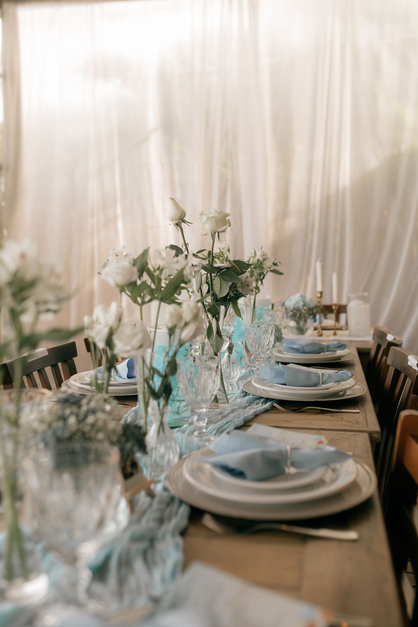 Long table set with white roses and blue glassware